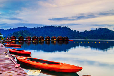 Boats moored in lake against sky during sunset