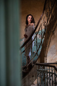 Portrait of woman standing by railing against wall