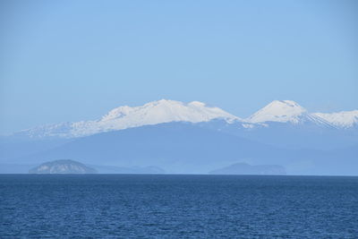 Scenic view of sea and mountains against clear blue sky