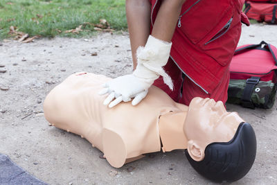 Midsection of paramedic performing cpr on mannequin