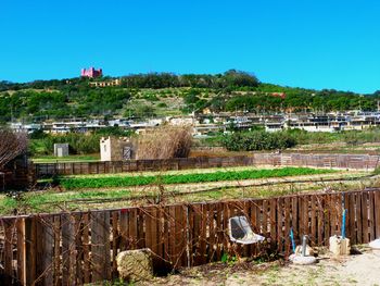 Houses and trees on field against clear blue sky
