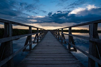 Footbridge over sea against sky during sunset