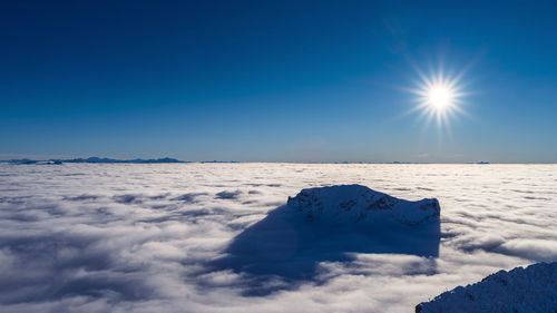 Scenic view of snow covered mountains against bright sun