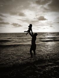 Silhouette woman standing on beach against sky