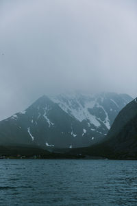 Scenic view of lake by snowcapped mountains against sky