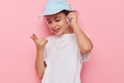 Portrait of young woman holding gift against pink background