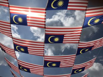 Low angle view of flags against cloudy sky