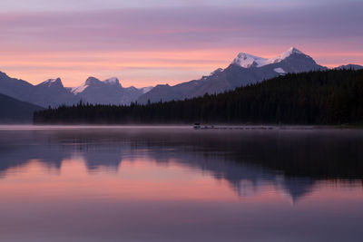 Scenic view of lake by mountains against sky during sunset