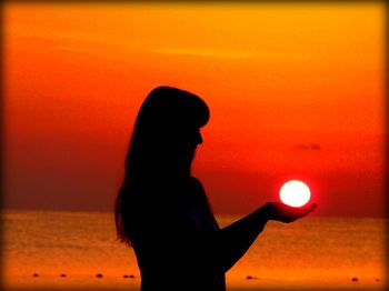 Silhouette of people on sea at sunset