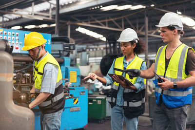 Engineers in an industry plant setting up machines vs a background of a machine factory.