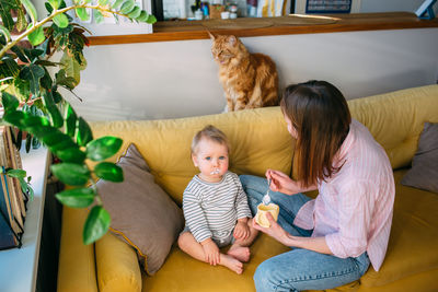 Mom feeds a small child at home with yogurt from a spoon. family concept