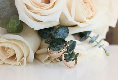 Close-up of wedding rings with bouquet on table