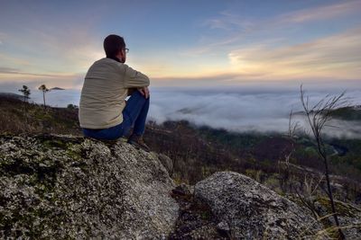 Man looking at view of rocks against sky during sunset