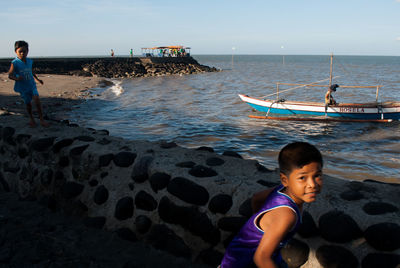 Boy standing on beach against sky