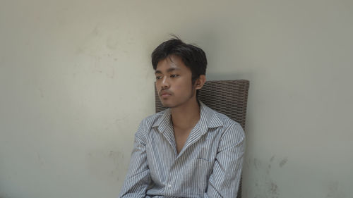 Portrait of young man standing against wall