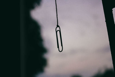 Close-up of metal hanging against sky