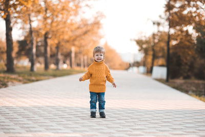 Portrait of boy standing on footpath