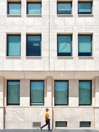 Side view of young man walking by building in city