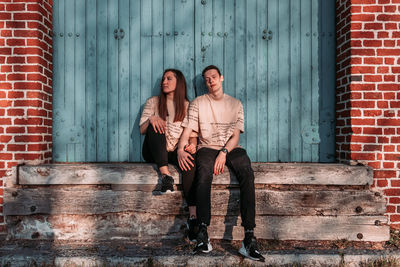 Full length portrait of young couple against wall