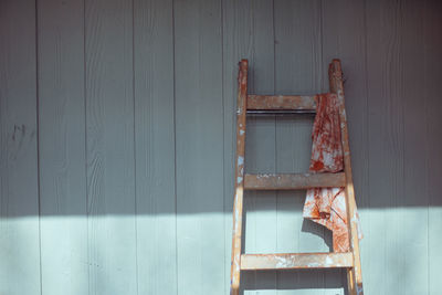 Close-up of wooden ladder with dirty cleaning rag on wall