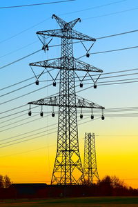 Low angle view of silhouette electricity pylon on field against sky