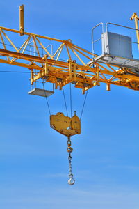 Low angle view of crane against clear blue sky