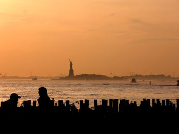 Silhouette people on beach against sky during sunset