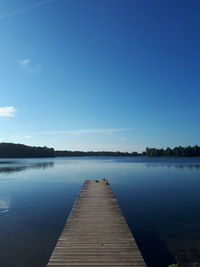 Pier over lake against blue sky