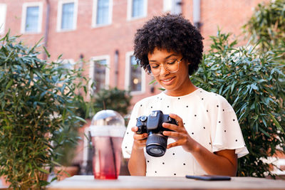 Woman using camera against plants