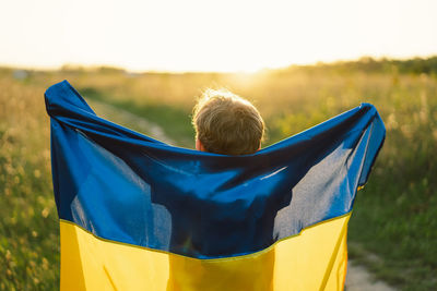 Ukrainian child boy in white t shirt with yellow and blue flag of ukraine in field.