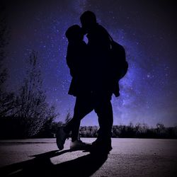 Silhouette couple standing against blue sky at night