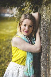 Portrait of woman leaning on weathered wall