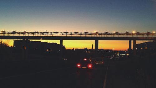 Silhouette bridge against sky during sunset in city