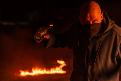 Side view of man standing by bonfire at night