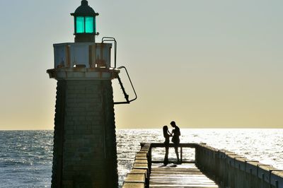 Rear view of man walking on pier over sea against clear sky