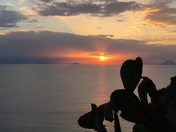 Silhouette people on shore against sky during sunset