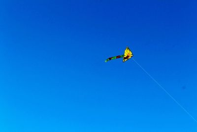 Low angle view of helicopter flying against clear blue sky