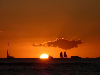 Silhouette sailboat on sea against orange sky