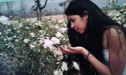 Side view of young woman looking at flowering plants