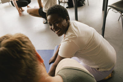 Smiling businesswoman rolling yoga mat by male colleague at workplace