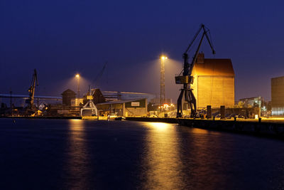 Illuminated pier at harbor against sky at night