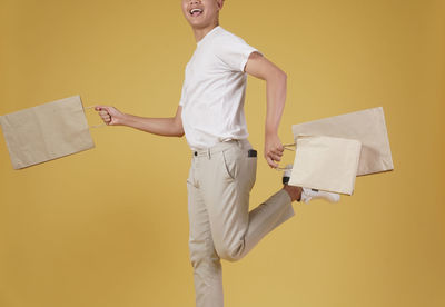 Side view of smiling man standing against yellow wall