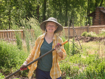 Portrait of smiling woman holding rake