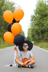 Portrait of smiling boy with balloons at street