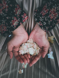 Two hands of a girl carrying tiny colorful leaf decoration on her skirt 