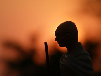 Silhouette man with stick against sky during sunset