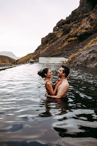 Couple laughing in water between mountains