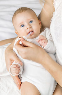 Mother feeding medicine to baby through pipette at home