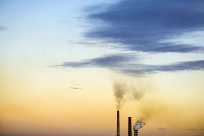 Smoke emitting from chimney against sky at sunset