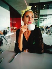 Thoughtful woman with coffee sitting in restaurant